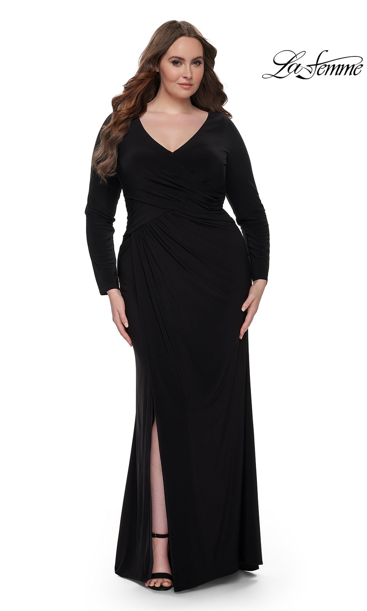 A woman models the La Femme Plus-Size Black Jersey Formal Dress 32191, featuring long sleeves, a V-neckline, and a front slit, against a white background. The La Femme logo is visible in the top right corner.